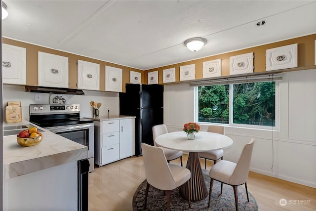 kitchen featuring white cabinetry, black fridge, stainless steel electric range oven, and light hardwood / wood-style flooring