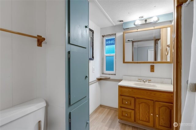 bathroom with wood-type flooring, vanity, a textured ceiling, and toilet