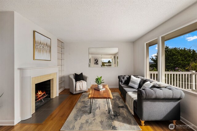 living room with baseboards, a textured ceiling, and wood finished floors