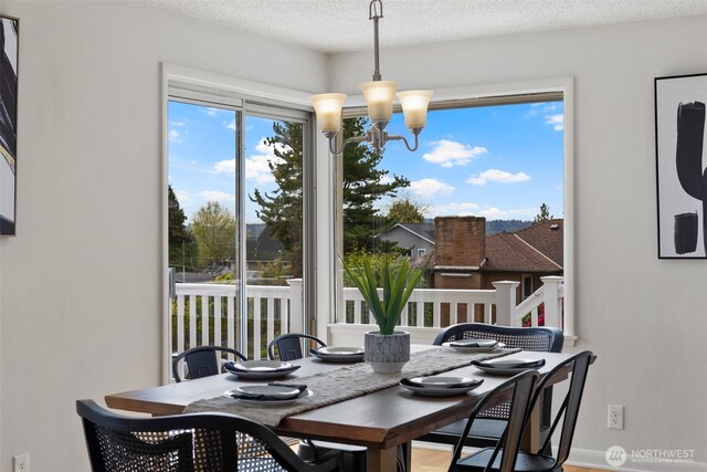 dining area with baseboards, a textured ceiling, and a chandelier