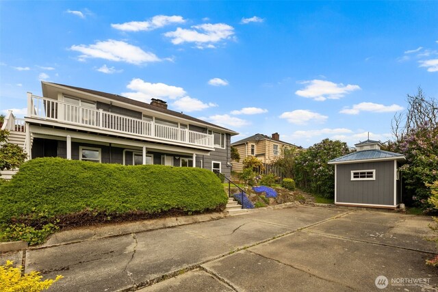 rear view of property with a balcony and a chimney