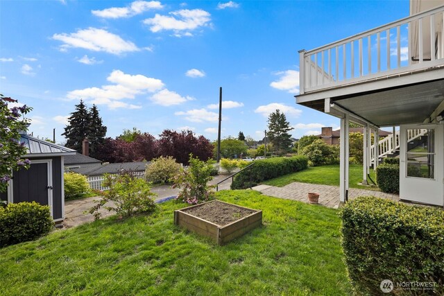 view of yard with a patio, fence, stairs, and a vegetable garden