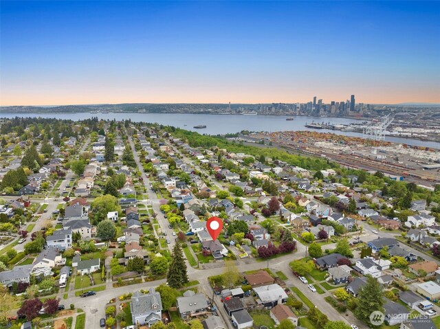aerial view at dusk featuring a water view and a residential view
