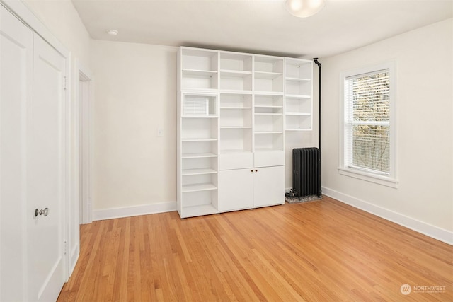 unfurnished bedroom featuring radiator heating unit and light wood-type flooring