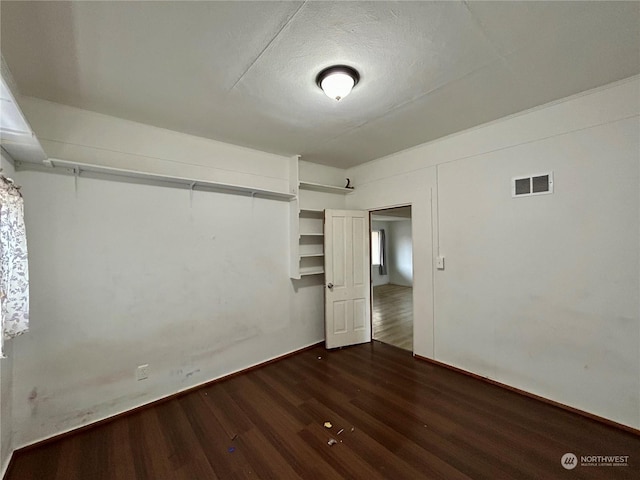 spare room featuring dark wood-type flooring and a textured ceiling