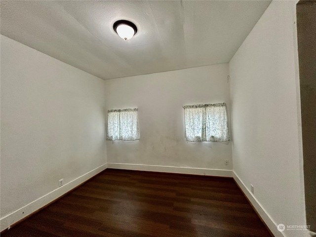 unfurnished room with dark hardwood / wood-style flooring