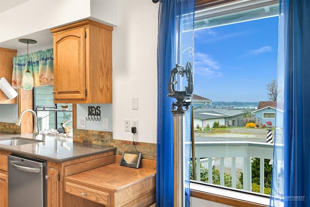 kitchen featuring stainless steel dishwasher, decorative light fixtures, backsplash, and sink