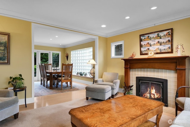 living room featuring a fireplace, ornamental molding, and light wood-type flooring