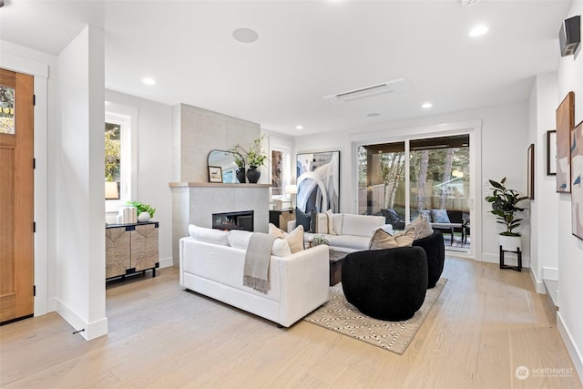 living room featuring a healthy amount of sunlight, a fireplace, and light hardwood / wood-style flooring