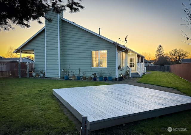 back of house at dusk featuring a yard, a chimney, fence private yard, and a wooden deck