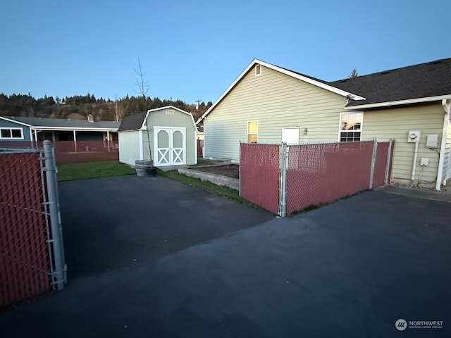 view of home's exterior featuring a storage shed, a gate, fence, and an outbuilding