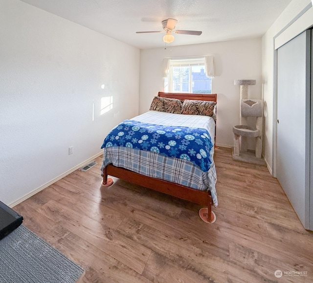 bedroom featuring baseboards, wood finished floors, visible vents, and a ceiling fan