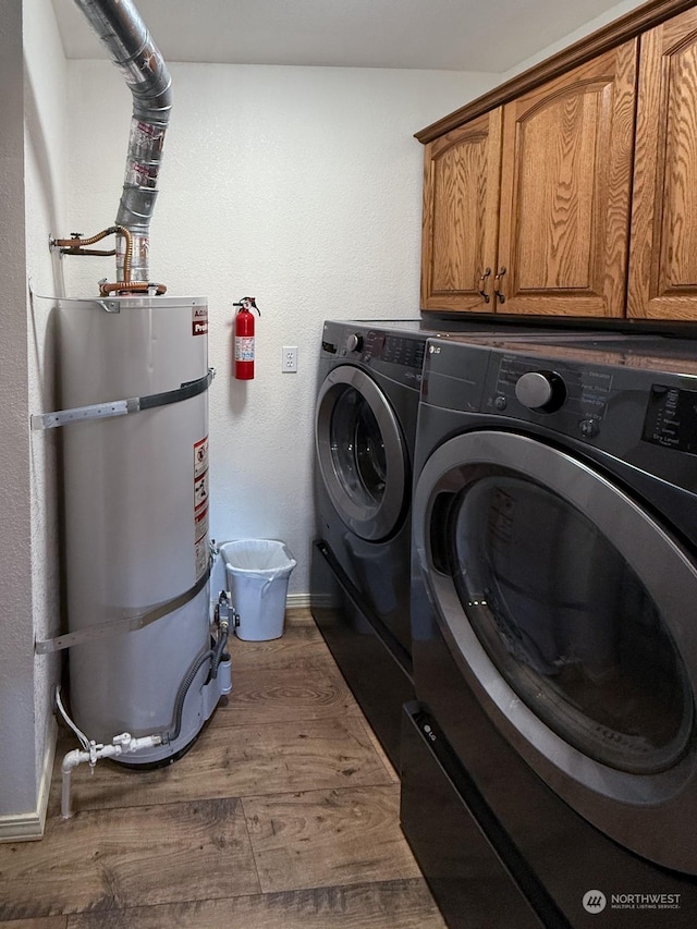 clothes washing area featuring water heater, washer and clothes dryer, cabinets, and dark hardwood / wood-style floors