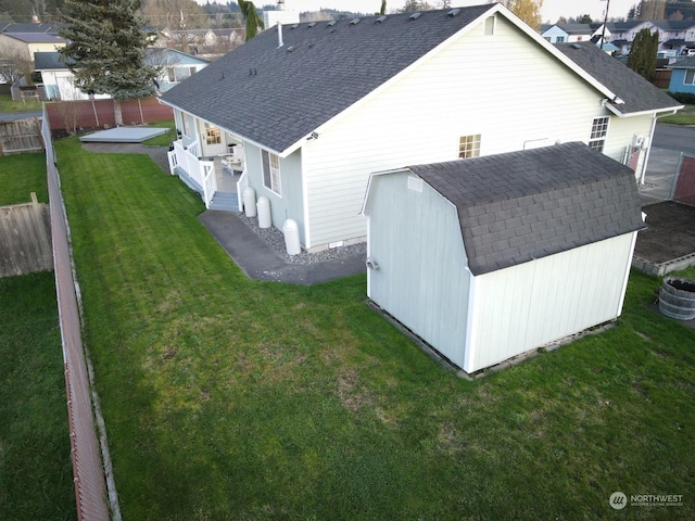 back of house with a storage unit and a lawn