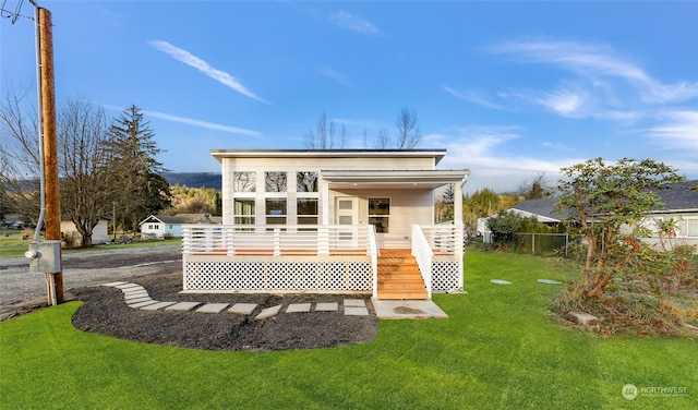 rear view of house featuring a lawn and a wooden deck