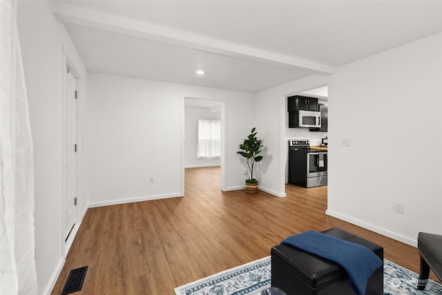 sitting room with beamed ceiling and wood-type flooring