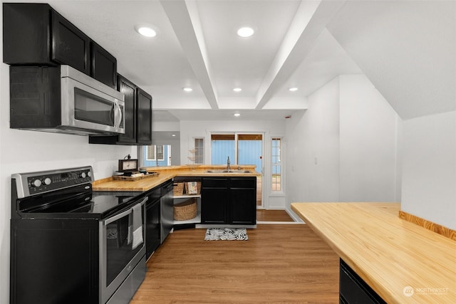 kitchen with appliances with stainless steel finishes, light wood-type flooring, kitchen peninsula, and sink