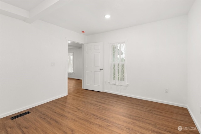 unfurnished room featuring wood-type flooring and beamed ceiling