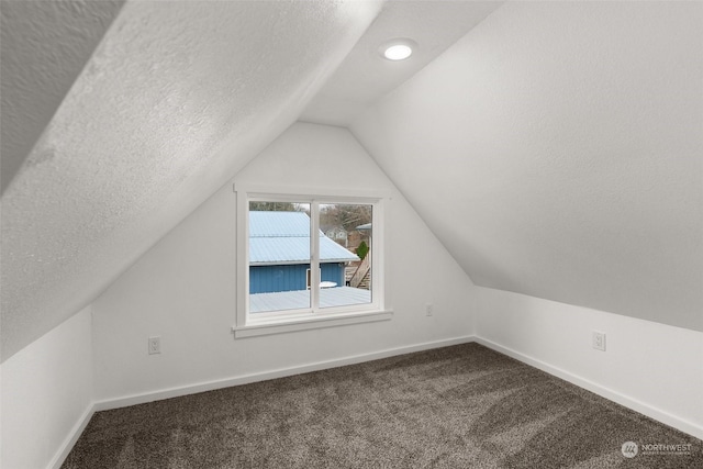 bonus room with a textured ceiling, vaulted ceiling, and carpet