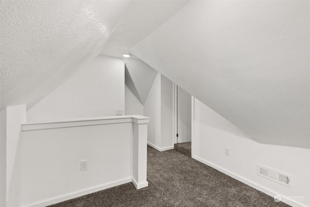 bonus room featuring lofted ceiling, a textured ceiling, and dark colored carpet