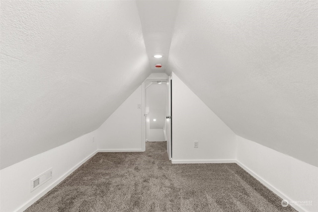 bonus room with a textured ceiling, carpet floors, and vaulted ceiling