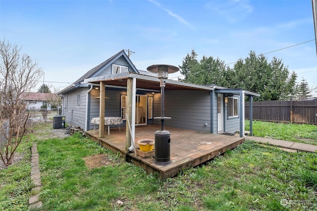 rear view of property with a lawn, a deck, and central AC