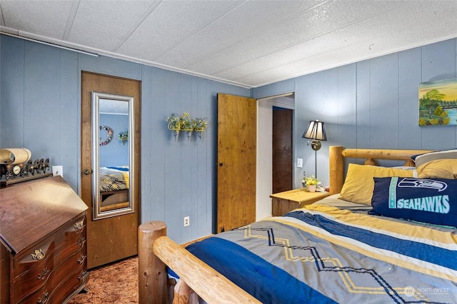 carpeted bedroom featuring wood walls