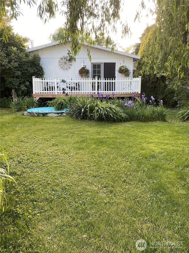 back of property featuring a lawn and a wooden deck