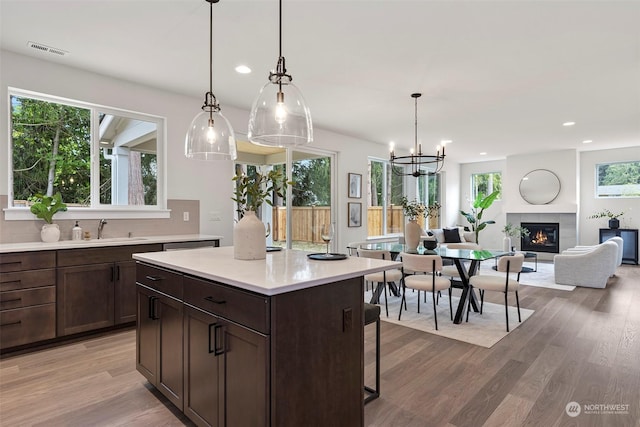 kitchen featuring a kitchen breakfast bar, sink, a fireplace, hardwood / wood-style floors, and hanging light fixtures