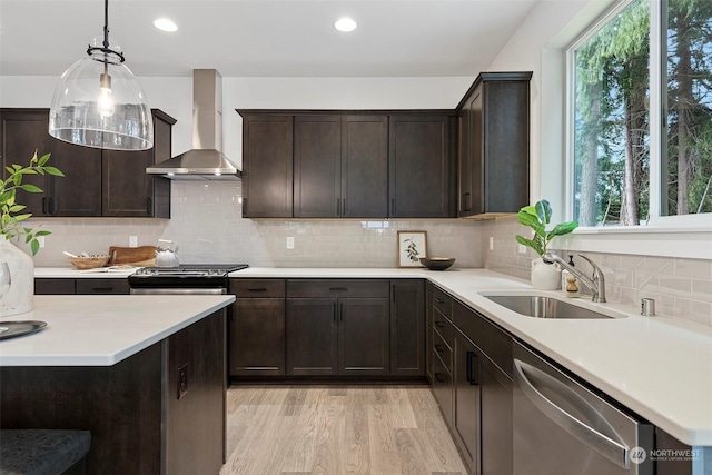 kitchen featuring appliances with stainless steel finishes, sink, a healthy amount of sunlight, and wall chimney range hood