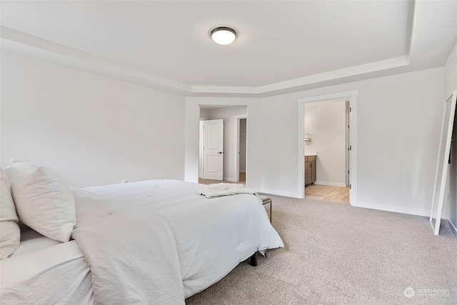 bedroom featuring ensuite bathroom and light colored carpet