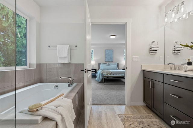 bathroom with hardwood / wood-style flooring, vanity, and a tub to relax in