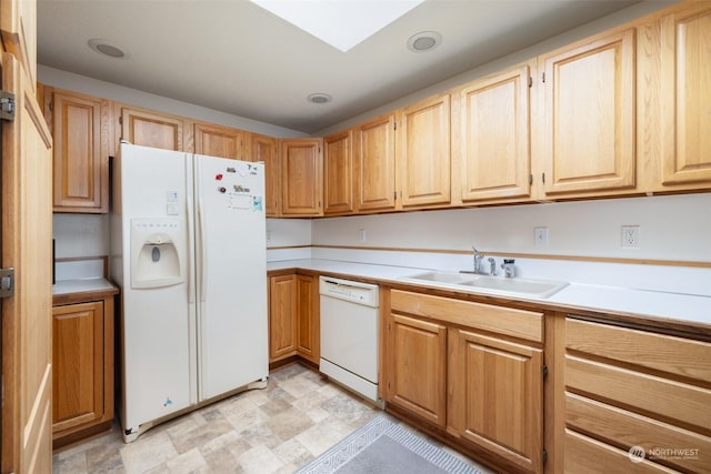 kitchen with light brown cabinetry, white appliances, and sink