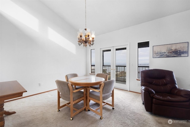 carpeted dining space featuring french doors and an inviting chandelier