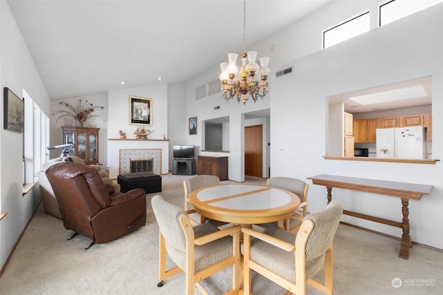 carpeted dining area featuring a healthy amount of sunlight, a towering ceiling, and an inviting chandelier