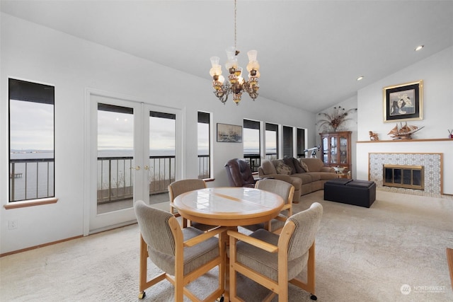 dining area with light carpet, a fireplace, lofted ceiling, and a notable chandelier