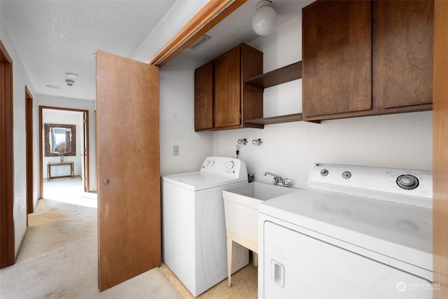 laundry area featuring cabinets, a textured ceiling, separate washer and dryer, and light colored carpet