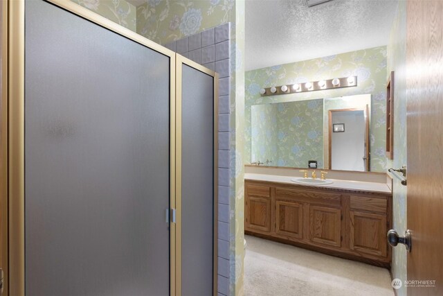 bathroom featuring vanity, a textured ceiling, and a shower with door