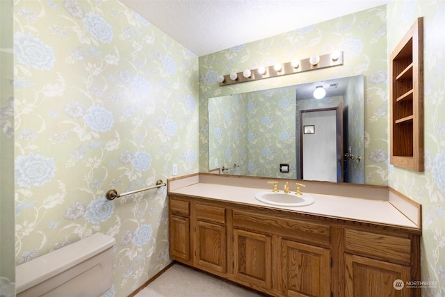 bathroom featuring vanity, toilet, and a textured ceiling