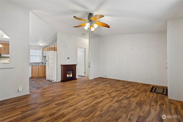 unfurnished living room featuring lofted ceiling, ceiling fan, dark wood-type flooring, and sink