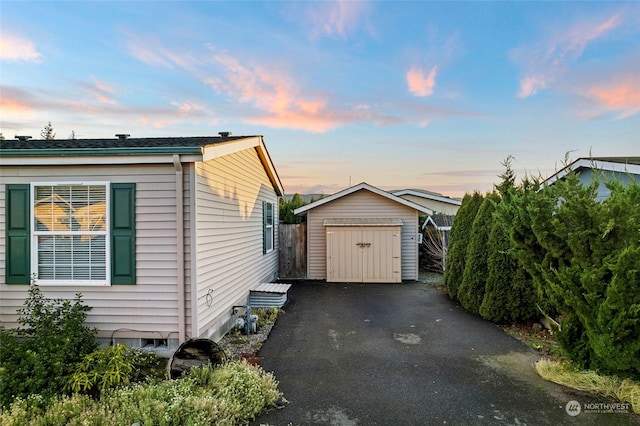 property exterior at dusk featuring a storage unit