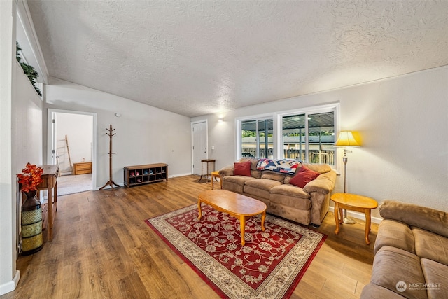 living room featuring lofted ceiling, a textured ceiling, and hardwood / wood-style flooring