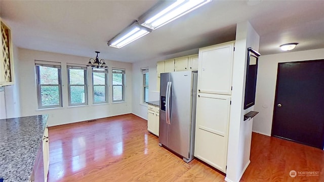 kitchen with white cabinetry, stainless steel refrigerator with ice dispenser, a notable chandelier, and light hardwood / wood-style floors