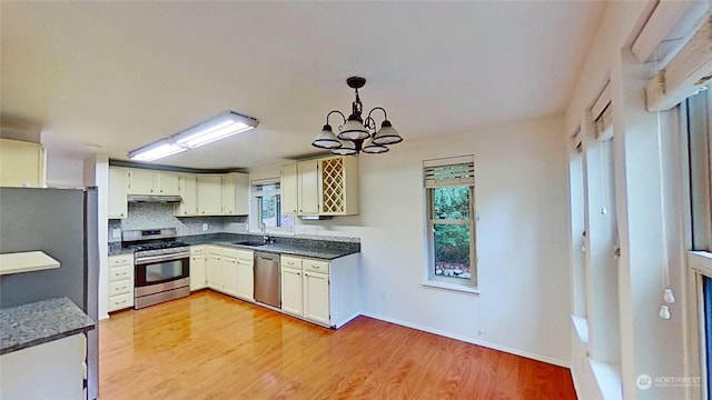 kitchen with stainless steel appliances, sink, light wood-type flooring, pendant lighting, and a healthy amount of sunlight