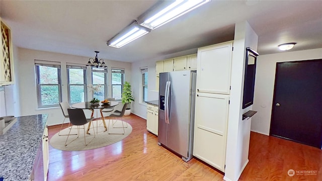 kitchen with white cabinetry, stainless steel fridge, a chandelier, and light wood-type flooring