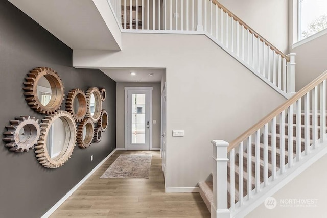 entryway featuring a towering ceiling and light wood-type flooring