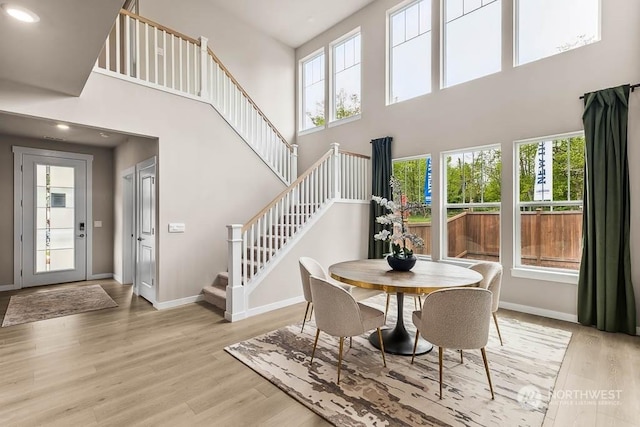 dining room with a towering ceiling, light hardwood / wood-style flooring, and a healthy amount of sunlight