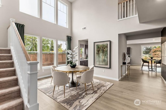 dining area with a towering ceiling and light hardwood / wood-style flooring