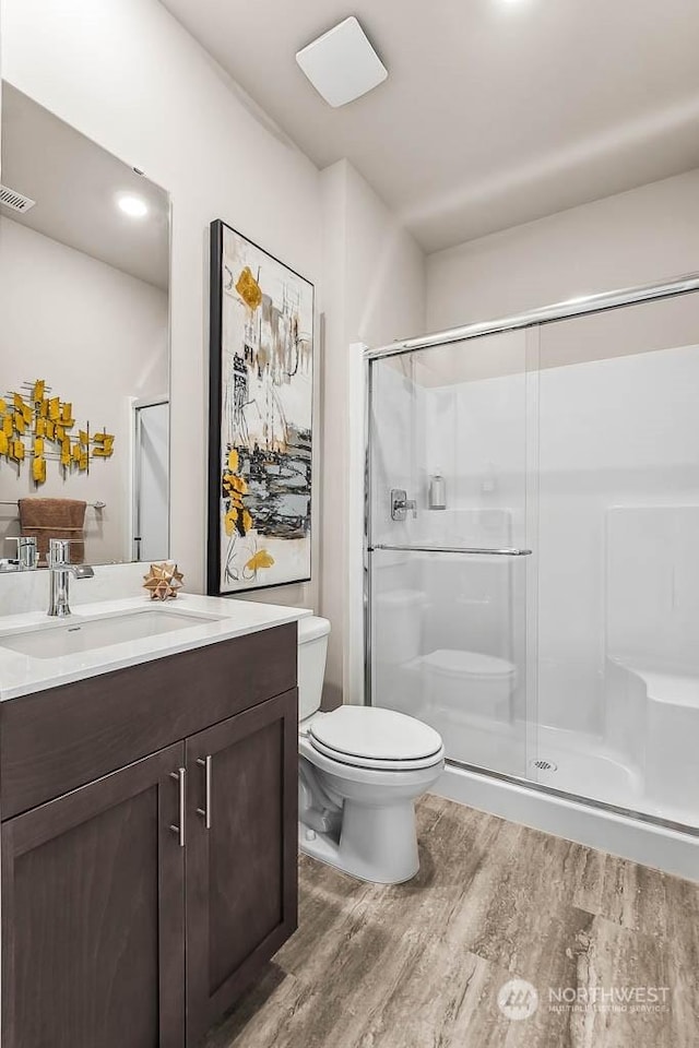 bathroom featuring hardwood / wood-style flooring, toilet, and a shower with shower door