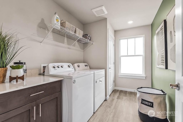 clothes washing area featuring separate washer and dryer and light hardwood / wood-style flooring